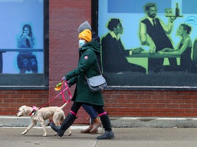 Pedestrians walk past a mural showing diners in northeast Calgary on Thursday, May 20, 2021.