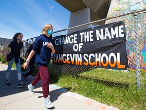 Langevin School students in Calgary walk past a sign calling for the school name to be changed on Monday, May 31, 2021.