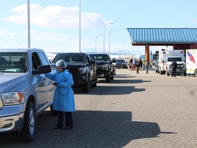 A health-care worker talks to a driver on the American side of the Carway Border crossing in Montana on Wednesday, April 21, 2021. A long line of cars were backed up at the Carway Border crossing in southern Alberta as First Nations members and others from the general public took advantage of free vaccinations courtesy of the Blackfeet Tribe in Montana.