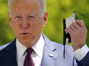 President Joe Biden pulls off his face mask as he arrives to speak about loosening COVID-19 mask guidelines outside the White House on April 27.