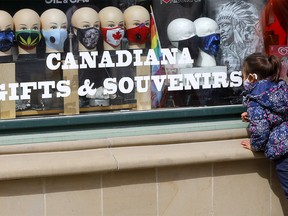 A small child looks over masks at a storefront on Stephen Avenue mall in downtown Calgary as COVID cases continue to rise on Monday, May 3, 2021.