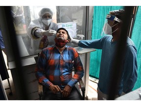 A health worker collects a nasal swab sample from a man to test for the COVID-19 coronavirus at a civil hospital in Amritsar on May 13, 2021.