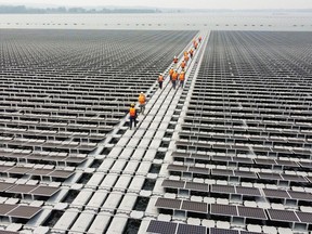 Workers walk between solar cell panels over the water surface of Sirindhorn Dam in Ubon Ratchathani, Thailand on April 8, 2021. Canada has the potential to be a world leader in renewable energy, says Nigel Topping, UN High-Level Champion for Climate Action for the COP26 climate summit in Glasgow in November.