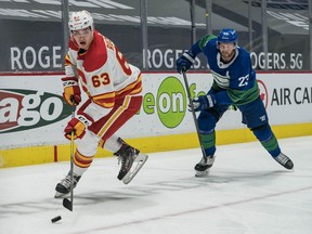 Calgary Flames forward Adam Ruzicka carries the puck with Vancouver Canucks defenceman Alexander Edler chasing at Rogers Arena in Vancouver on Sunday, May 16, 2021.