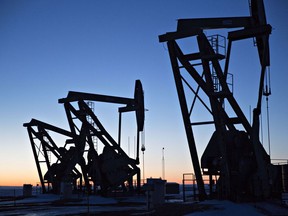 The silhouettes of pumpjacks are seen above oil wells in the Bakken Formation near Dickinson, North Dakota.