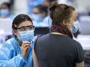 A health care worker administers a COVID-19 vaccination at the Bill Durnan Arena in Montreal on April 21, 2021.