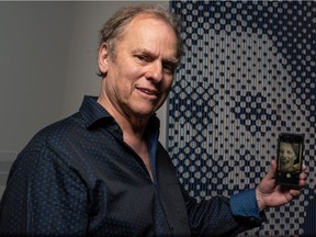 Artist Chris Cran poses for a photo with one of his art works, Large Blue Laughing Woman, showing how the piece is supposed to be viewed, from a distance or through a phone camera, at Contemporary Calgary on Tuesday, June 15, 2021. Azin Ghaffari/Postmedia