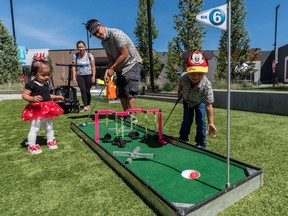 Savannah, 1.5, her parents Carol Yeung and Vince Ho, and her brother Liam, 4, play with the Tee off for Father's Day outdoor mini-golf activation at Deerfoot City on Friday, June 18, 2021. The Father's Day event is available from June 18-20 and appointments must be booked at Deerfoot City's website.