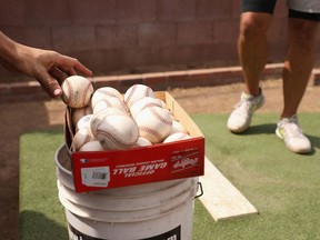Baseballs are taken from a box as MLB pitchers practise in a backyard throwing session in this photo from June 2020 in Scottsdale, Ariz.
