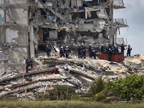 Members of the South Florida Urban Search and Rescue team look for possible survivors in the partially collapsed 12-story Champlain Towers South condo building on June 26, 2021, in Surfside, Florida.