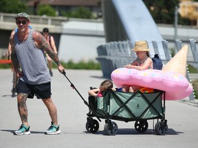 Jeremy Hoffart is joined by wife Chelsea (not shown) as he pulls his kids Isla and Indie in a cart with their melted ice cream float on the St Patrick's Bridge in Calgary on Sunday, June 27, 2021. Jim Wells/Postmedia