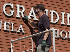 Crews from Edmonton Catholic Schools remove the Grandin name from Grandin Elementary School, 9844 110 St., in Edmonton Monday June 28, 2021. Monday morning Edmonton Catholic School Board trustees unanimously voted to rename the school and remove a mural of Bishop Vital Grandin from the exterior of the school. Grandin was an advocate for the Indigenous residential school system.
