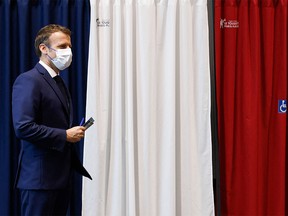 French President Emmanuel Macron leaves a polling booth equipped with anti-COVID curtains before casting his ballot as he votes at a polling station in Le Touquet, for the second round of the French regional elections on June 27, 2021.