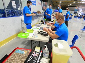Staff prepare supplies at the pop-up COVID-19 vaccination clinic at the Village Square Leisure Centre in northeast Calgary on Sunday, June 6, 2021.