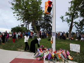 People are seen at a makeshift memorial at the fatal crime scene where a man driving a pickup truck jumped the curb and ran over a Muslim family in what police say was a deliberately targeted anti-Islamic hate crime, in London, Ontario, Canada June 7, 2021.