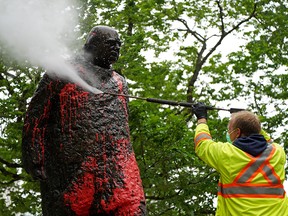A worker washes the statue of Sir Winston Churchill near city hall in Edmonton on Thursday, June 17, 2021, after it was vandalized with red paint.
