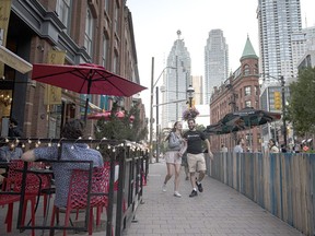 Pedestrians walk through an outdoor dining area of a restaurant in downtown Toronto, Ontario, Canada, on Saturday, June 19, 2021. Ontario is now allowing limited outdoor dining and public gatherings, after the province cleared the vaccination threshold required to move into its first stage of reopening.
