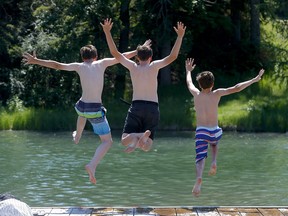 Friends L-R, Grady Larson, 12, Kyler Brown, 12, and Spencer Banks, 13, cool down at the lagoon at Bowness Park as temperatures soared in Calgary on Tuesday, June 29, 2021.