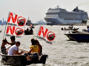 Environmental protesters from the "No Grandi Navi" group, demonstrate aboard small boats against the presence of cruise ships in the lagoon, as the MSC Orchestra cruise ship (Rear) leaves Venice across the basin on June 05, 2021. The cruise ship, which arrived in Venice on June 03, 2021 for the first time in 17 months, signalling the return of tourists after the coronavirus pandemic but enraging those who decry the impact of the giant floating hotels on the world heritage site, picked up about 650 passengers on June 05, before heading south to sample the delights of Bari, Corfu, Mykonos and Dubrovnik.