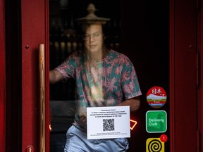 A man goes out of a restaurant with a door sign for visitors indicating that guests must first register in the restaurant via a QR code before they can take a seat, in Moscow on June 22, 2021. - Moscow authorities announced on June 22, that residents will soon have to present an anti-Covid pass to enter restaurants, as the city battles a surge in infections driven by the Delta variant. From June 28, restaurant-goers will have to present a QR code showing a negative coronavirus test valid for three days -- or proof they have been vaccinated or were sick with coronavirus within the previous six months.