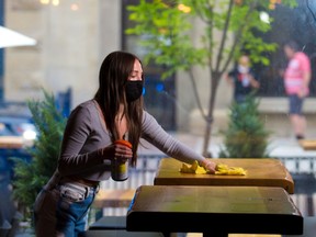 Ashlin Parker gets tables ready in the El Factory Warehouse restaurant on Stephen Avenue Mall in Calgary on Wednesday, June 9, 2021. Stage two of Alberta's reopening plan begins June 10, which will allow indoor dining for up to six people.