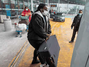 International air travellers load their luggage onto a shuttle bus to take them to one of the quarantine hotels Monday, February 22, 2021 in Montreal.