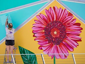 Courtney Hansen with Student Works Painting touches up a mural that had graffiti on it on Olympic Way S.E. in Calgary on Tuesday, June 22, 2021.