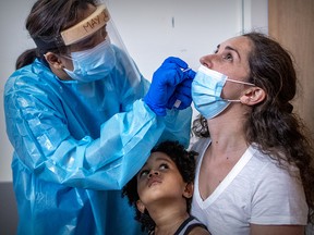 Sonia Egron receives a COVID-19 test as son Noah watches in a testing clinic in Montreal on July 16, 2020.
