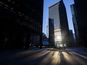 Light reflects off buildings as a lone pedestrian is seen during morning commuting hours in Toronto's financial district during the pandemic.