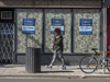 A pedestrian wearing a mask walks past a shuttered business on Toronto’s Queen Street on March 24, 2021.