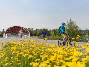 People spend the warm summer afternoon on the Bow River pathway by the Peace Bridge on Tuesday, July 27, 2021.