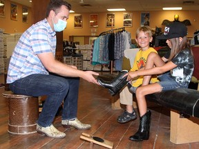Ben Grewing, director of Alberta Boot Company, helps seven-year-old Kale Hartsook and his nine-year old sister Kenadie pick out some boots at the local western wear shop on Monday, July 12, 2021.