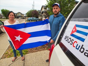 Anne Marie Harmsen and her husband Jose Gonzalez Estevez hold a Cuban flag outside their home in Chestermere on Wednesday, July 21, 2021. The Cuban-Canadian family is part of local protests calling for democracy and an end to dictatorship in Cuba.