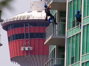 Window washers clean the glass on the Arriva tower in Calgary’s Victoria Park area on Monday, July 26, 2021.