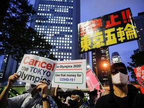 People hold signs as they participate in a rally calling for the cancellation of the 2020 Olympic Games, one month from the official start of the games, in Tokyo, Japan on June 23, 2021.