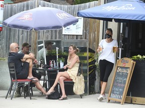 People lounge on a restaurant patio on Queen Street East in Toronto on June 19, 2021.