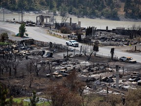 An RCMP vehicle drives past the remains of vehicles and structures in Lytton, B.C., on Friday, July 9, 2021, after a wildfire destroyed most of the village on June 30.