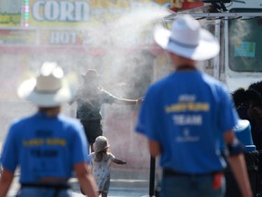 Visitors cool off in a mist shower at the Calgary Stampede midway on Saturday, July 17, 2021.