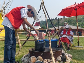 Kelvin Crowchief makes berry soup as Belva Wings cuts meat for smoking on the pit-fire at Elbow River Camp at Calgary Stampede on Thursday, July 15, 2021.