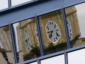 The Old City Hall clock is reflected in windows in downtown Calgary on Oct. 28, 2020.
