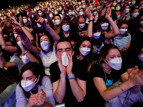People wearing protective masks attend a Love of Lesbian concert at the Palau Sant Jordi, the first massive concert since the start of the pandemic, in Barcelona, Spain, March 27, 2021.