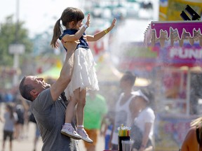 Ian Hauser lifts his niece Alina Hauser into cooling mist at the Calgary Stampede Slush Zone on Tuesday, July 13, 2021.