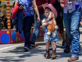 Three-year-old Austen takes a walk on the Stampede midway with his father on Monday, July 12, 2021.