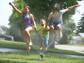 Left to right: Mimi, Niels and Aksel Chapman beat the heat by running through a sprinkler at their Highwood home on July 9, 2021.