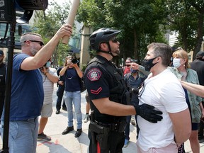 Two groups with opposing views clash during a rally against the lifting of COVID-19 health orders at McDougall Centre in Calgary on Friday, July 30, 2021.