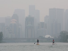 FILE - It was another smoke shrouded day in Calgary as two stand up paddleboarders cruised down the Bow River towards downtown on Monday, July 19, 2021.
