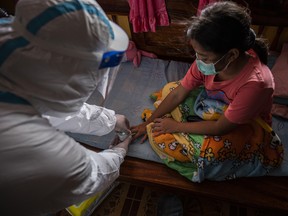 A volunteer gives an oxygen saturation reading to a girl under home isolation in a neighbourhood heavily stricken with COVID-19 on July 26, 2021, in Bangkok, Thailand.