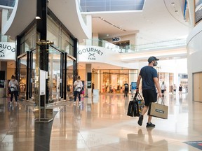 A shopper exits a store holding multiple shopping bags in Sherway Gardens mall during the stage two reopening.