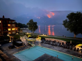 A wildfire burns on a hillside in Osoyoos, B.C., with a resort in the foreground on July 20, 2021.
