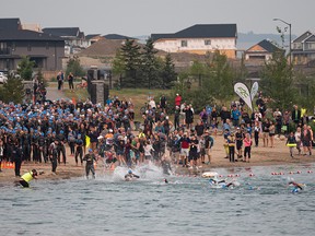 Athletes enter Harmony Lake in Rocky View County to start the first part of the Ironman Triathlon on Sunday, Aug. 1, 2021.